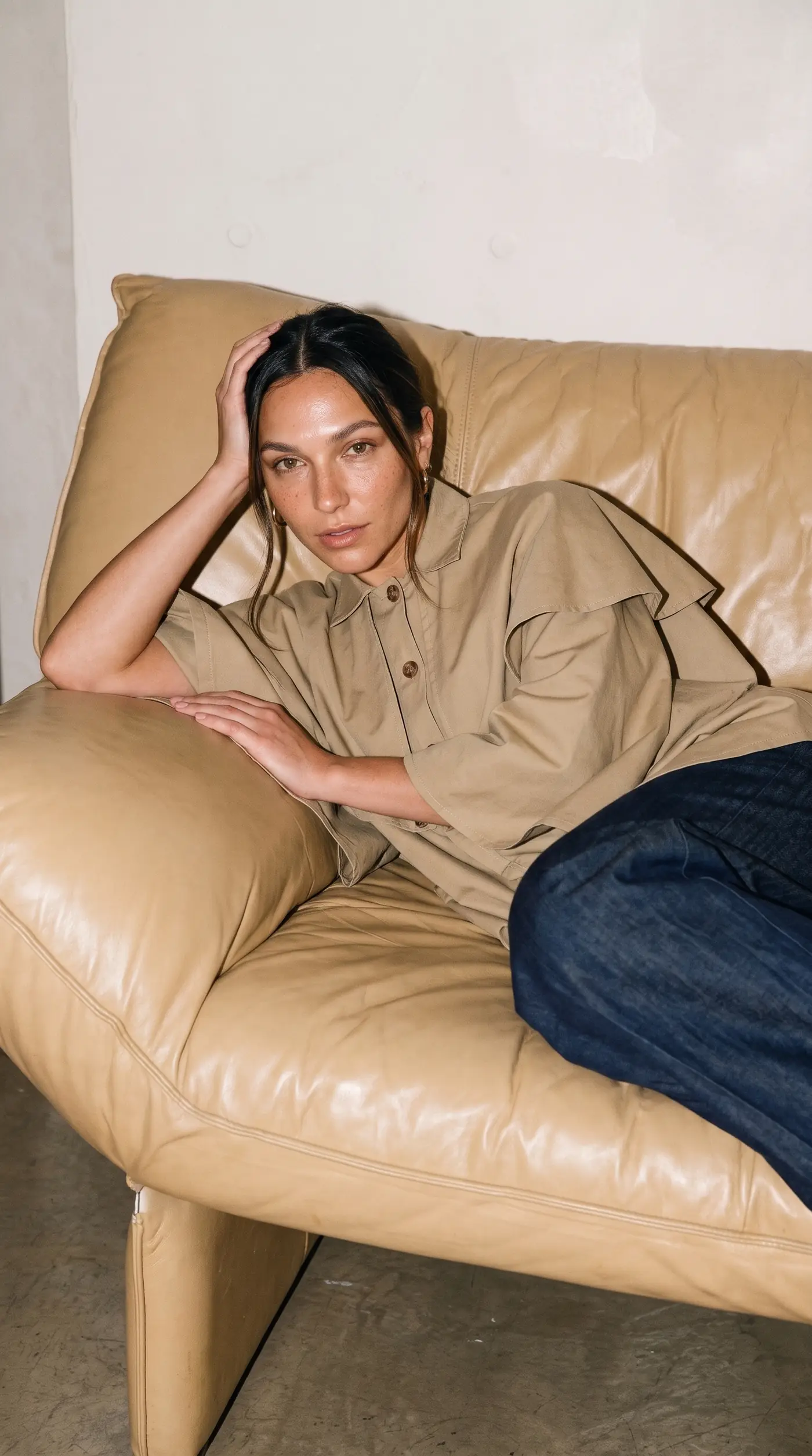 Femme portant la Veste-cape courte Marie Lestyle, assise dans un fauteuil en cuir