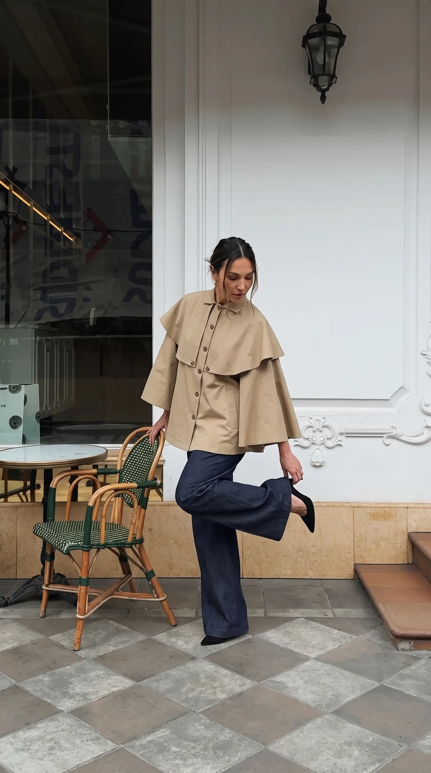 Veste-cape courte portée devant un café parisien