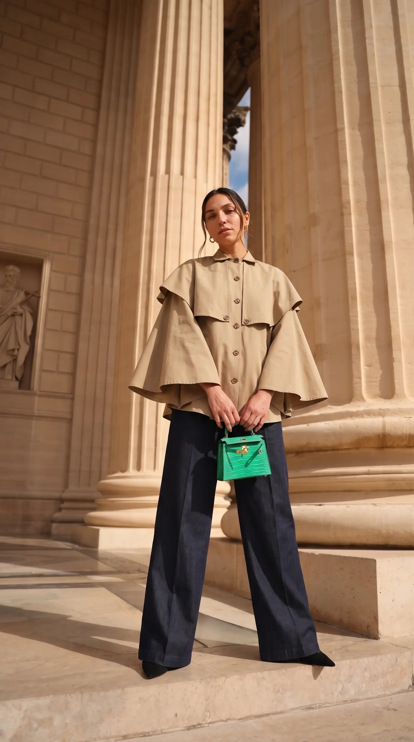 Femme portant la Veste-cape courte Marie Lestyle entre des colonnes, à Paris